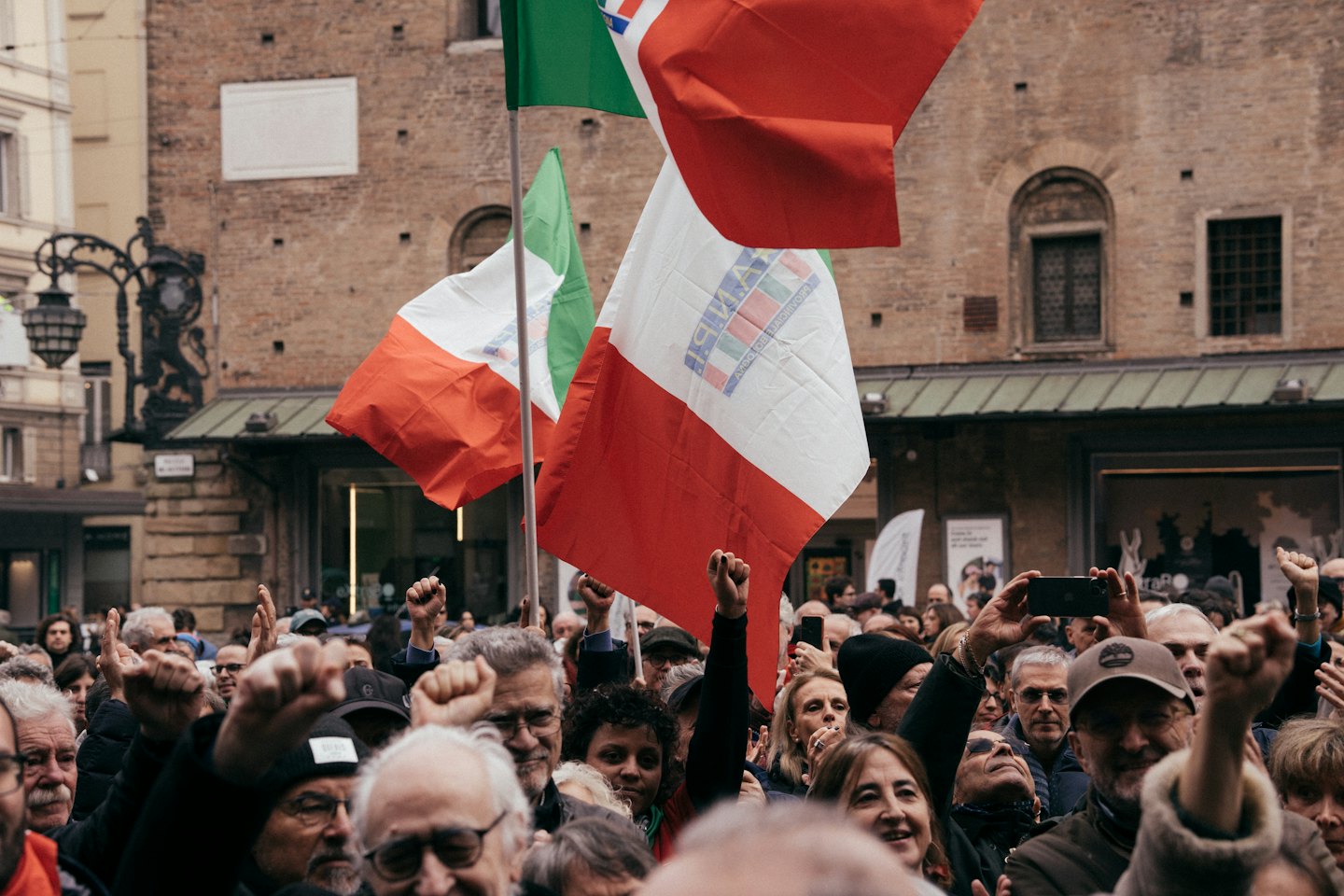 Folla di manifestanti con bandiere italiane durante una manifestazione.