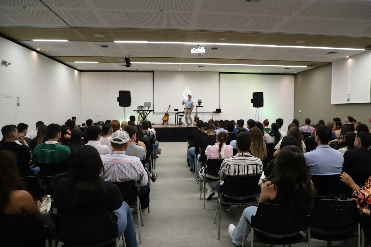 Un relatore parla a un pubblico attento in un moderno auditorium.