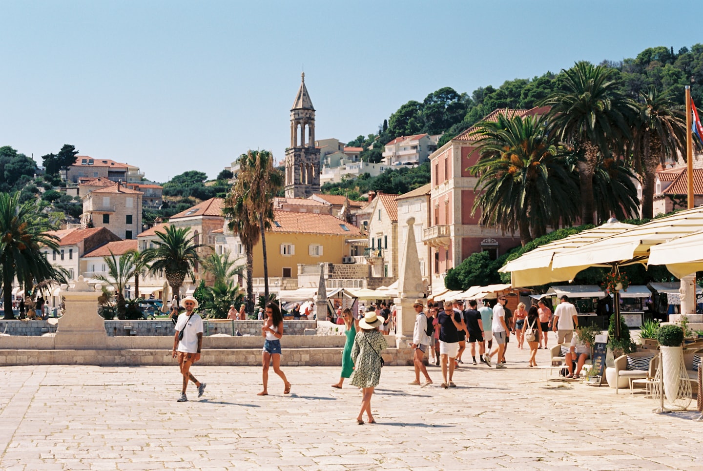 Persone che si godono una giornata di sole in una vivace piazza mediterranea.