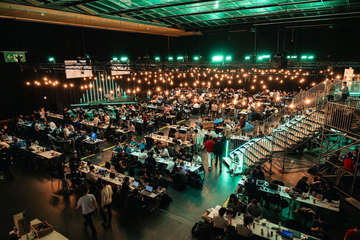 Giovani adulti diversi collaborano a tavoli in un grande salone per eventi.