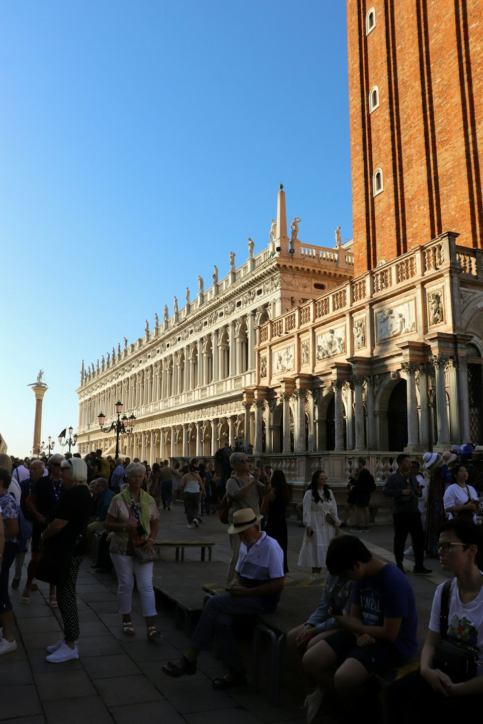 Persone ed edifici storici in una piazza europea soleggiata.